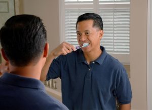 Man Brushing His Teeth Looking in The Mirror